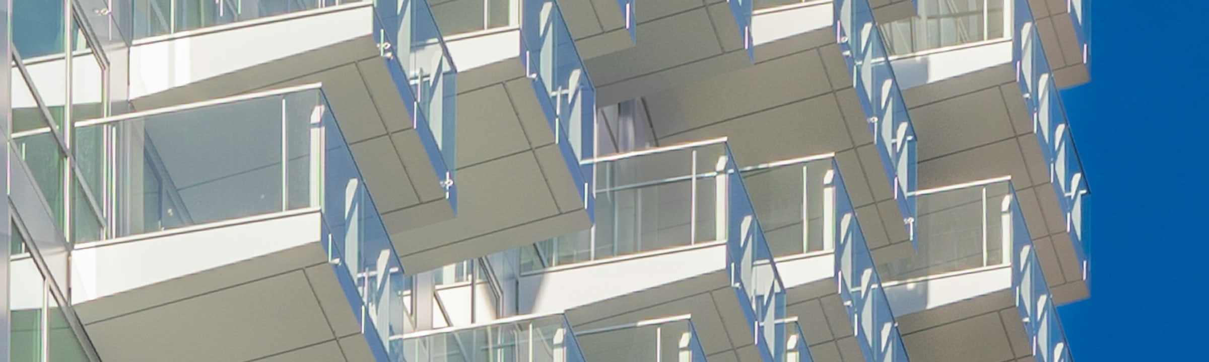 A residential tower: white balconies stepping across the facade against a clear sky